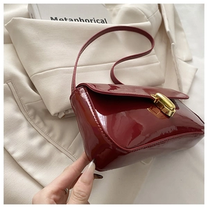 Nahaufnahme der burgunderroten Lackledertasche mit goldenem Verschluss-Detail
