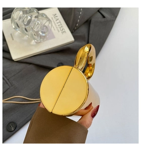 Detail of a luxurious gold mirror finish metal clutch bag with fine chain and artistic props