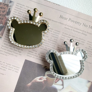 Detailed close-up of rhinestone bear-shaped makeup mirror with crown in gold and silver