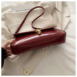 Detailaufnahme der Vintage-Handtasche aus weinrotem Lackleder mit goldenem Drehverschluss