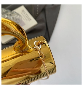 Detail of glossy gold metallic handbag with sleek chain strap and lobster clasp connector