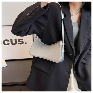 Silver metallic crescent underarm bag worn by a model in a black blazer suit