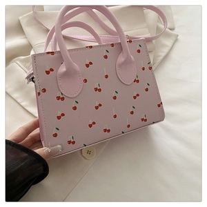 Détail du mini sac à main rose avec motifs cerises rouges et finition en cuir PU texturé