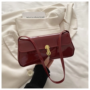 Detail der weinroten Lackleder-Baguette-Tasche mit ovaler goldener Metallschnalle und Naht