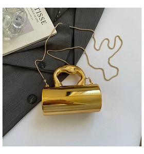 Macro shot of mirror-finish gold cylindrical handbag with sculptural handle and chain