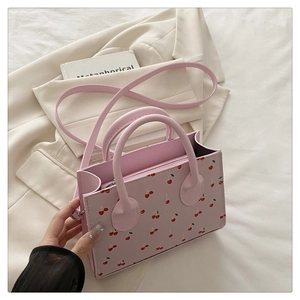 Détail du sac à main en similicuir rose avec imprimés cerises et fermeture éclair en métal