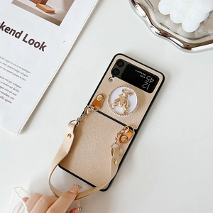 Detail of Galaxy Z Flip case featuring a golden bear charm and premium leather wrist strap