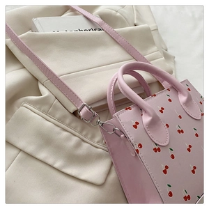 Gros plan du sac à main rose imprimé cerise avec boucles argentées et bandoulière