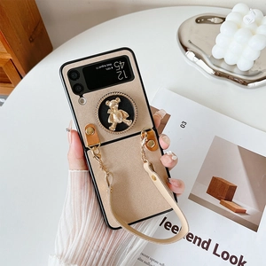 Detail of beige leather fold phone case with golden bear stand and elegant hand chain