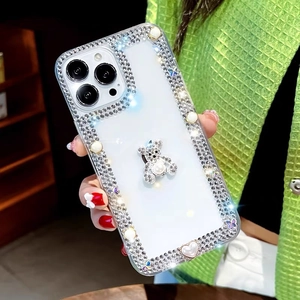 Détail d'un ours en strass et perles sur une coque iPhone transparente à la main