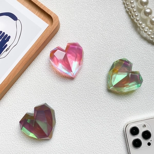 Detail of colorful faceted heart-shaped phone grips on a wooden tray with pearls