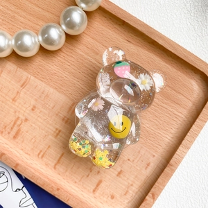 Close-up of bear-shaped phone grip with glitter, floral patterns and a happy smiley face