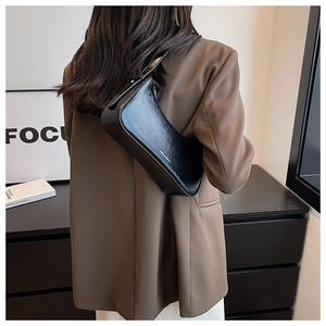 Chic black glossy leather underarm bag shown on model with adjustable strap detail