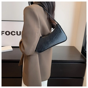 Matte black leather underarm bag with vintage texture worn with a brown blazer