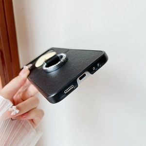 Detail of black faux leather phone case with rhinestone ring holder and heart charm