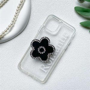 Detail view of transparent iPhone case with black floral rhinestone grip and Romantic text