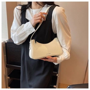 Detail of a creamy white faux leather baguette bag showing texture and printed logo