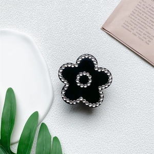 Detail of a black flower hair claw clip with sparkling rhinestones in a lifestyle setting