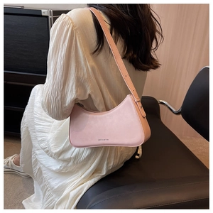 Adjustable strap detail on a pink leather baguette shoulder bag shown on a model