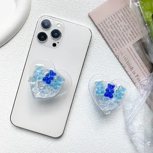 Macro detail of heart-shaped phone grip with blue bear charms and ice textures