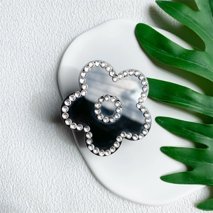 Close-up of black flower phone grip with sparkling rhinestones on a white tray