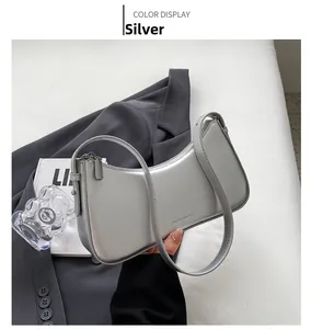 Close-up of silver crescent underarm bag with minimalist brand logo and textured finish