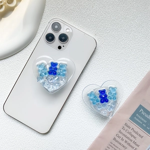 Close-up of heart-shaped phone grip tok with cute gummy bears on white stone background
