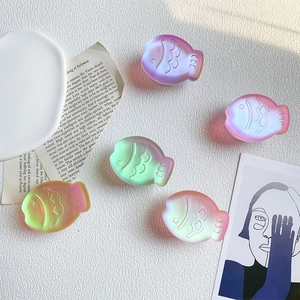 Artistic detail of 5 colorful matte resin fish-shaped phone grips with soft sunlight