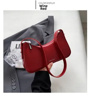 Detail of wine red matte leather baguette bag with silver zipper and long shoulder strap