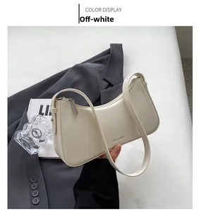 Close-up of a minimalist cream white baguette bag with subtle metallic zipper detail