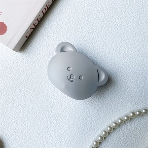 Close-up of a matte grey bear phone socket holder on white textured surface