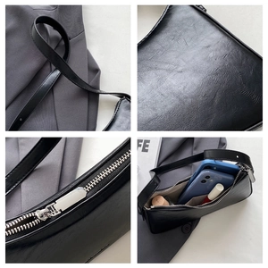 Detail view of black vintage texture underarm bag showing silver zipper and internal capacity