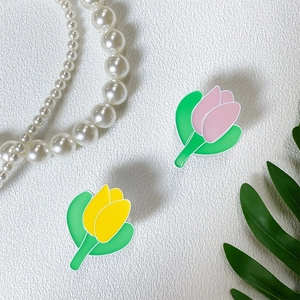 Detail view of pink and yellow tulip flower phone grips on a textured white surface
