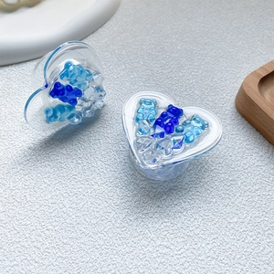 Macro view of a heart-shaped phone grip filled with blue bears and sparkling glitter