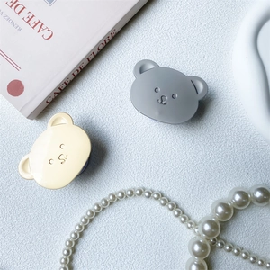 Close-up of cute bear-shaped retractable phone holders in matte yellow and grey colors