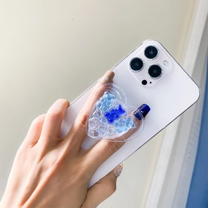 Close-up of heart-shaped phone grip with blue bear sequins on a white smartphone