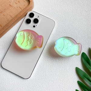 3D laser-cut iridescent fish-shaped expandable phone grip holder on white smartphone