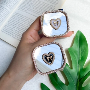 Close-up of square mirror phone stands with sparkling rhinestones and golden heart bow design