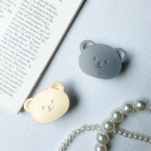 Close-up of cute bear phone stands in grey and cream on a stylish white textured background