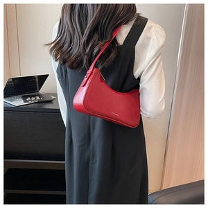 Detailed view of red leather crescent underarm bag worn by model in a minimalist setting