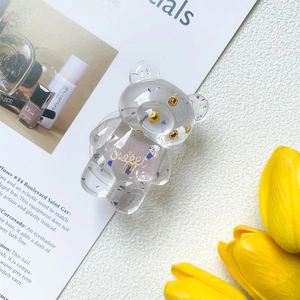 Close-up of a cute transparent bear phone grip with sparkling purple glitter and gold beads