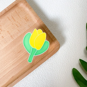 Detail of yellow tulip phone grip on wooden tray with a clean and natural aesthetic