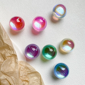 Macro shot of colorful glitter crystal balls with sparkling sand inside on textured background