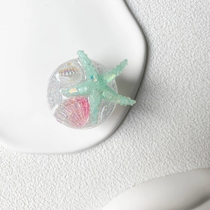 Detail of glitter ocean phone socket with resin starfish and shells on white tray