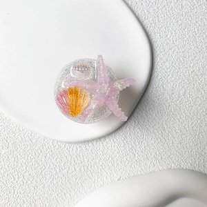 Macro detail of summer ocean phone grip featuring purple glitter starfish and seashell