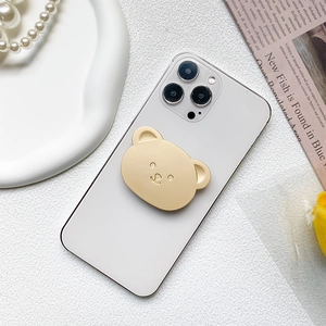 Cute golden bear collapsible phone grip holder mounted on a white smartphone
