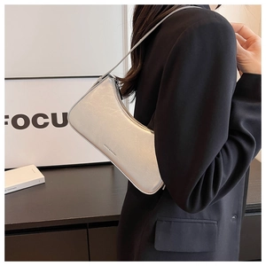 Silver metallic shoulder bag with zip closure styled on model in black blazer jacket