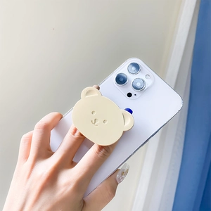 Close-up of cute cream bear phone grip holder mounted on a white smartphone for steady use