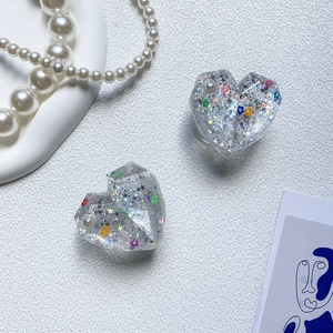 Macro detail of heart shaped phone socket with glitter, pearls and floral resin patterns