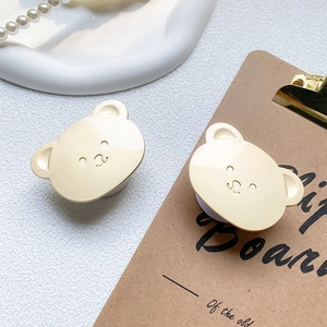 Detail of two cute cream-colored bear-shaped expandable phone stands on a white tray